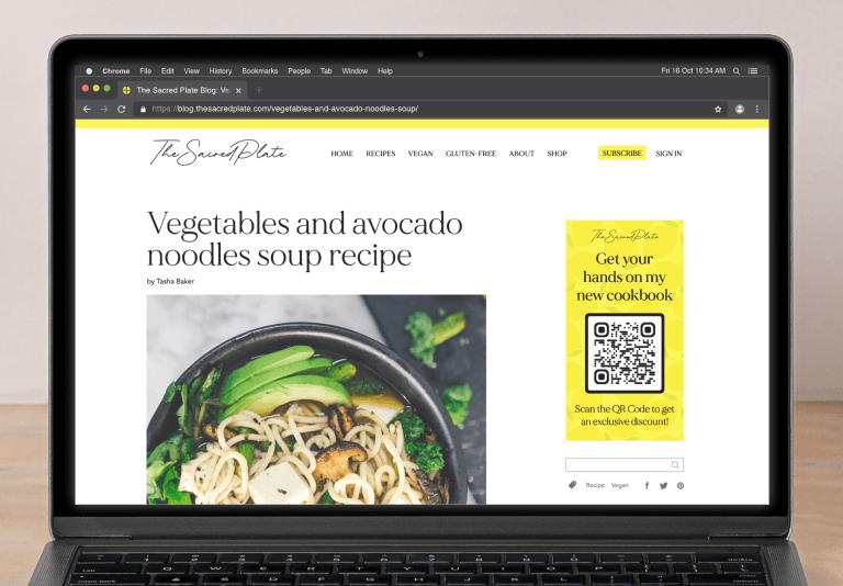 The Sacred Plate Website is displayed on a laptop next to headphones, a notebook, a pen, a bowl, a vase, and a smartphone.