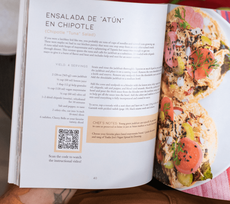 A person holding a cookbook that has a QR Code inside in the kitchen.