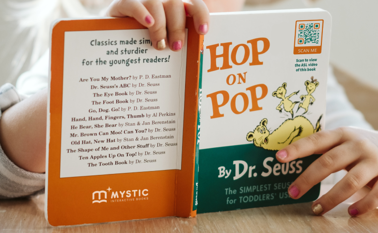 A child holds a book which has a QR Code image that links to an ASL video.