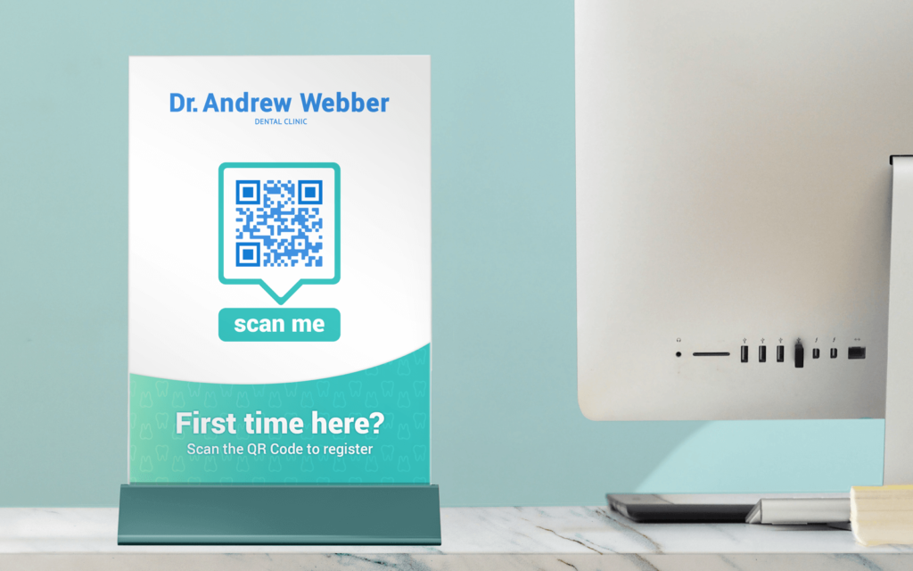 A table sign at dentist office reception desk shows a QR Code for patients to check-in for their visit online.