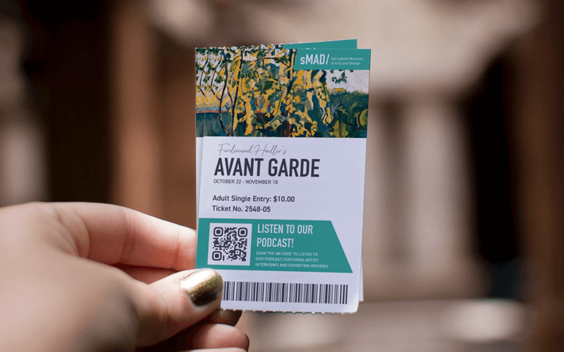 A hand holding a ticket with a QR Code and a barcode on it.