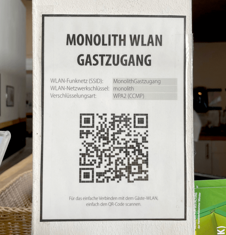 A black and white poster on a pillar advertises the gym’s wifi password in German with a QR Code.