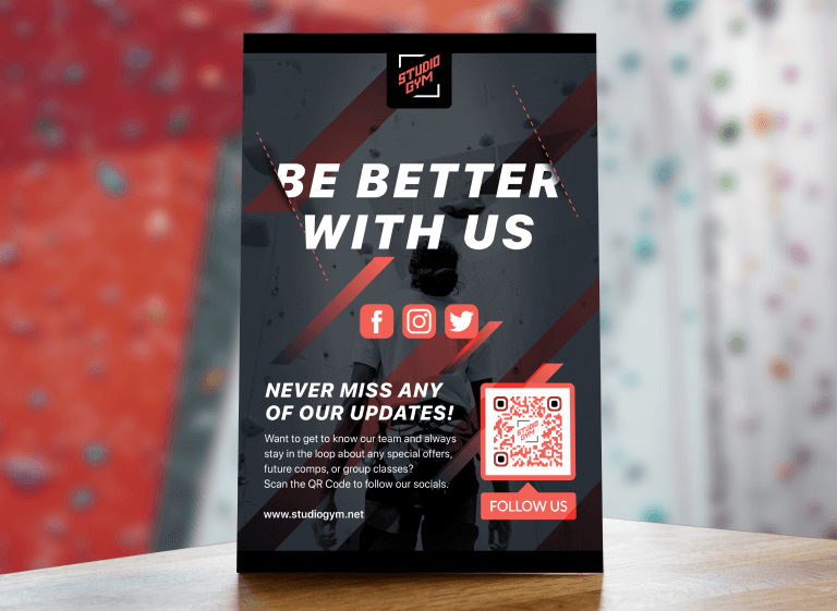 A black and red table tent on a wooden table with text advertising a climbing gym’s social media channels by scanning the QR Code.