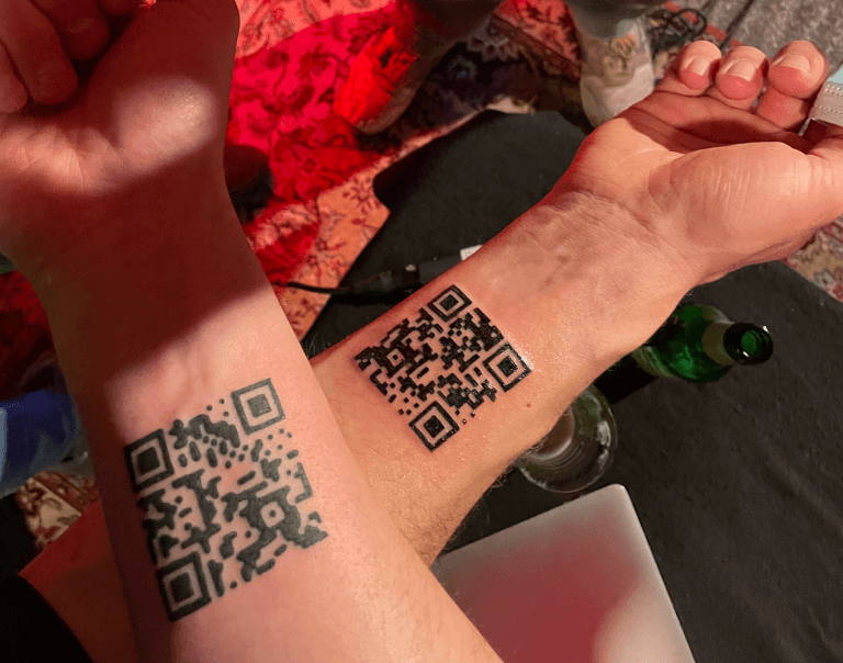 Two arms with QR Codes tattooed on the inside of the wrists.