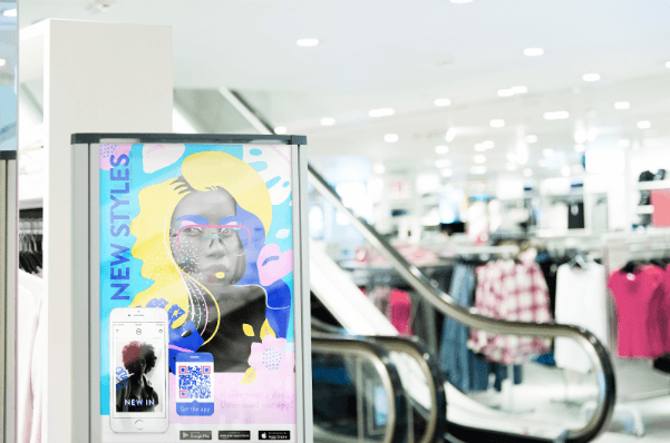 An App QR Code displayed on a banner next to an escalator.