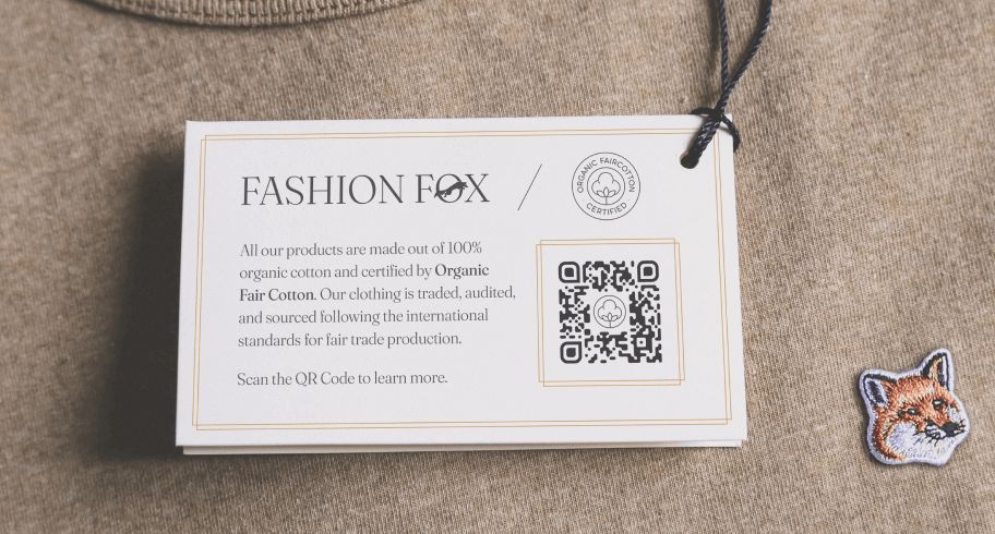 A beige sweater with a fox logo and a white label with a 2D Barcode on top.