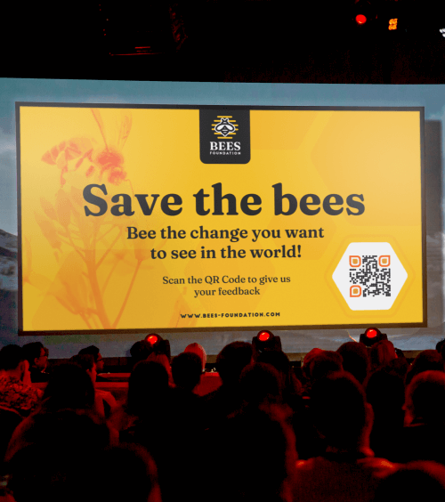 A screen projector displays a non-profit organization’s presentation with a QR Code that leads audiences to an online feedback form.