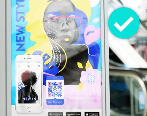 A billboard advertisement with a smartphone and QR Code next to it, next to a blue check mark.