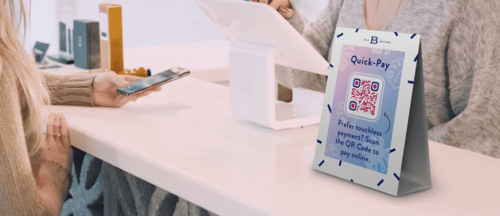 Two women in a retail store and a QR Code tent at the point of sale counter.
