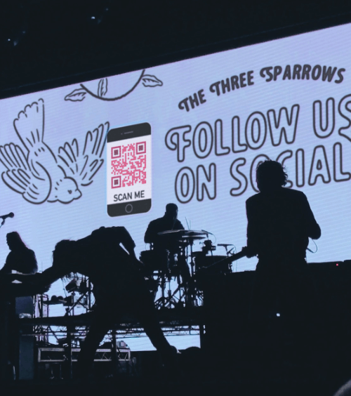 A stage display at a concert with a QR Code that displays a band’s social media channels.